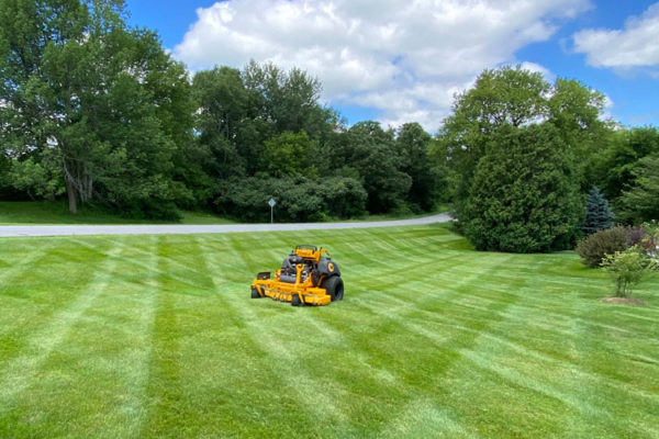 person on a standing commercial mower mowing